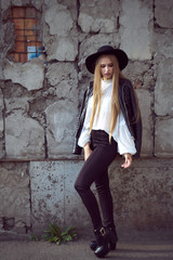 Young Caucasian brunette woman girl in black hat on concrete wall