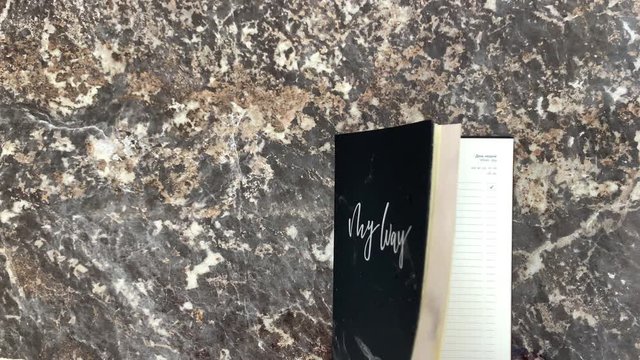 Incredible cosmic beautiful black diary on a black marble background, opens and you can make notes. Scrolling pages. Top view.