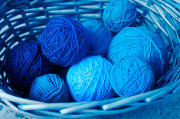 wicker basket with balls of wool yarn for knitting. classic blue color 2020 year trend