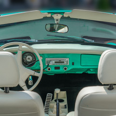 Interior and dash board of a classic car with the steering wheel and the dashboard showing