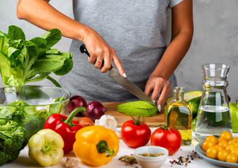Woman cuts avocado and cooking salad in the kitchen. Healthy diet concept.
