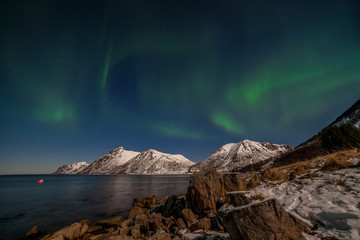 Fototapeta na wymiar Dramatic aurora borealis, polar lights, over mountains in the North of Europe - Lofoten islands, Norway
