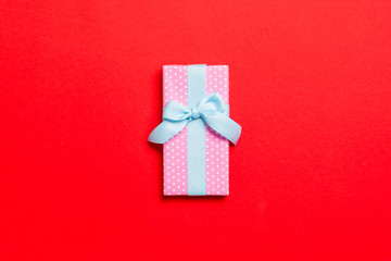 wrapped Christmas or other holiday handmade present in paper with blue ribbon on red background....