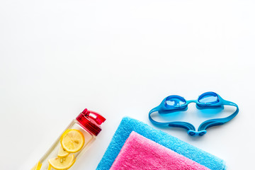 Swimming concept. Swim glasses, water bottle, towel on white background top-down frame copy space