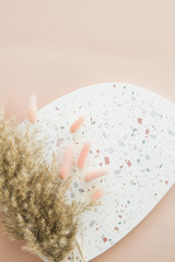 Dried pampa grass and bunny tail grass on terrazzo dish, pink background, copy space