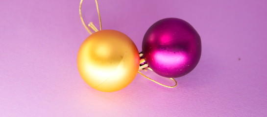 two christmas balls one yellow and one purple in a purple background
