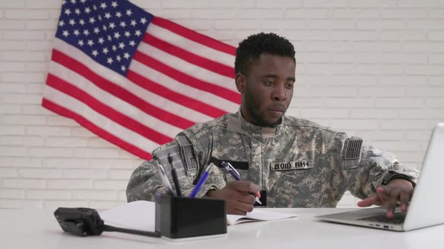 Afro-american soldier in uniform working seriously in office