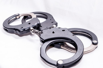 Two pair of handcuffs, one black and the other black and silver on a white background