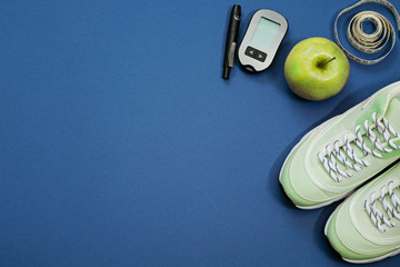 Flat lay with diet diabetes weight loss concept - Sneakers, tape measure, glucometer on a blue background. Place for text