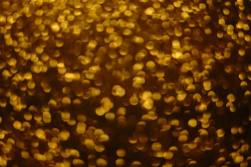 Golden shiny rain, gold round sparkles blurred background.