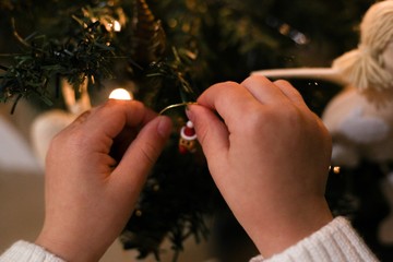 Baby decorating Christmas tree with toys. Kid’s hands hanging Christmas toy upon a tree - 309394740