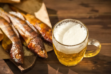 Beer glass with beer and hot smoked fish close-up. Beer mug with beer and potato chips, crackers on a dark background and copy space.
