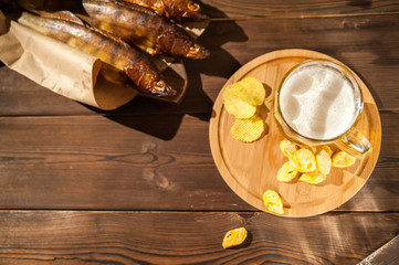 Beer glass with beer and hot smoked fish close-up. Beer mug with beer and potato chips, crackers on a dark background and copy space.