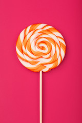 A large yellow Lollipop, on a scarlet background. Minimal concept with copy space.