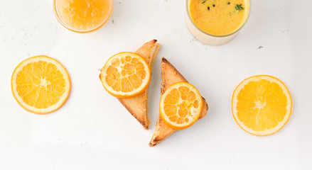 toasts with jam on a white plate next to slices of orange