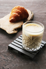 Glass of latte and croissant on a dark background
