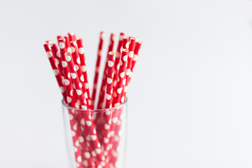 Red tubules for cocktails in a glass on a white background