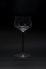 An empty wine glass on a black background.