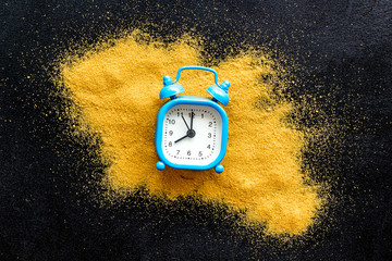Waste of time concept. Clock on sand on black background top-down