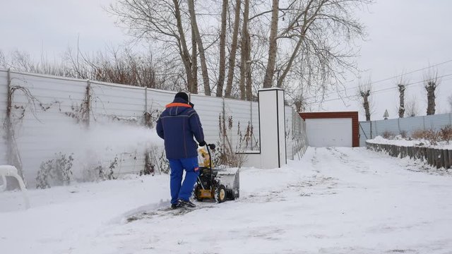 A man cleans snow from the tracks snowblower