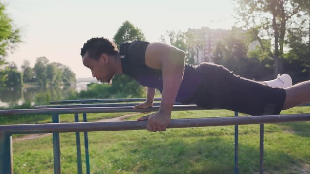 Muscular afro guy doing triceps dips on parallel bars