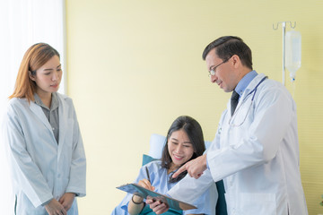 Obraz premium A professional doctor standing in a room with a patient lying in bed with an assistant doctor to prepare for a patient check up and consultant 