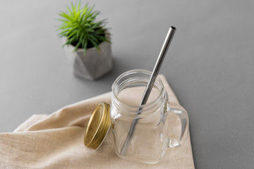 eco friendly concept - empty glass mug of with reusable metallic straw