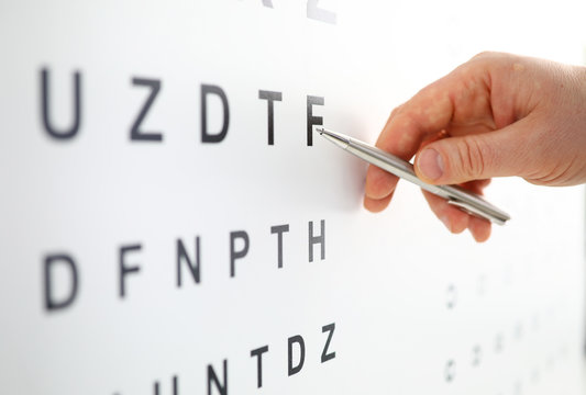 Silver ballpoint pen pointing to letter in eyesight check table