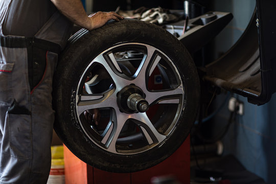 Wheel balancing or repair and change car tire at auto service garage or workshop by mechanic