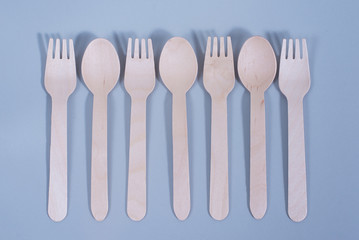 Brown wooden spoons and forks -cutlery lie on a light gray background. The concept of environmental protection, save nature, ecology plastic free, zero waste. No pollution land by plastic
