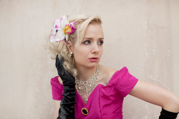 Portrait einer jungen Frau mit Perlenkette, Hibiskusblüte und pinken Kleid