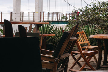 Wooden chairs in a green restaurant on the beach.