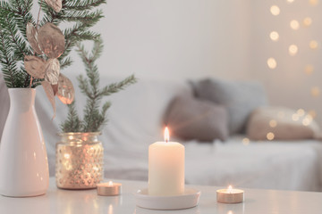 Christmas decorations with burning candles in white interior