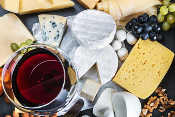 glass of red wine on the background of assorted cheeses, soft, hard, rennet and brine with fruits, nuts