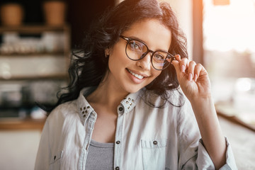 Cheerful female adjusting glasses in cafeteria