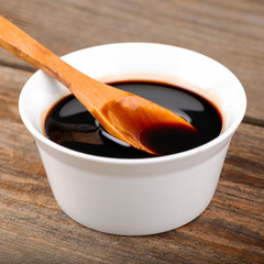 Homemade pomegranate sauce in a bowl with a spoon, fresh open pomegranate on a wooden background