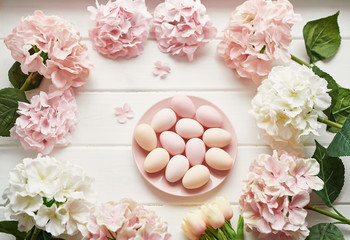 Obraz na płótnie Canvas Spring and Easter holiday greeting card concept. Pink and white hydrangeas, yellow tulips with pink eggs. Colorful easter eggs and branch with flowers. Postcard Template. Copy space. Flat lay.