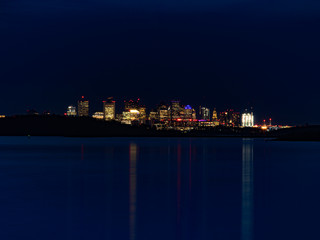 Fototapeta na wymiar Boston Skyline At Night with Blue Water and Sky