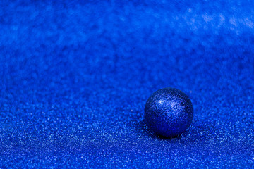 Glitter and shine classic blue ball on sparkling trendy blue background.