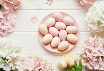 Spring and Easter holiday greeting card concept. Pink and white hydrangeas, yellow tulips with pink eggs. Colorful easter eggs and branch with flowers. Postcard Template. Copy space. Flat lay.