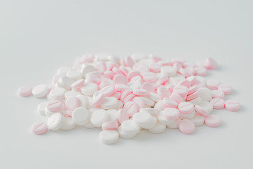 Pink and white pills on a light background. Medical pharmacy concept