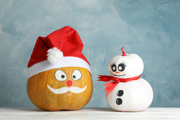 Snowman and pumpkin with Santa hat against blue background, space for text