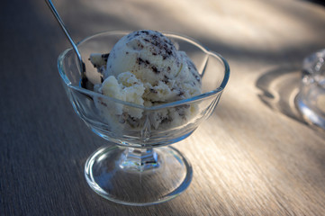 Fresh white light ice cream on wooden table, cup of glass with sundae, vanilla and chocolate, cold summer refreshing food