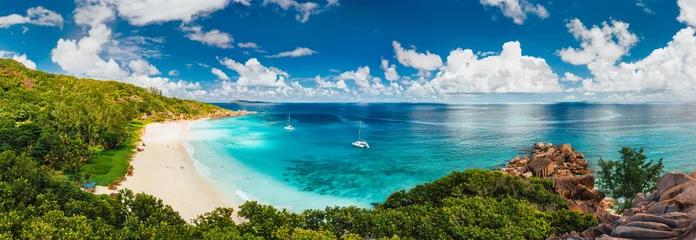 Fototapeten Aerial Pano von Grand Anse Beach auf der Insel La Digue auf den Seychellen. Weißer Sandstrand mit blauer Ozeanlagune und Katamaran-Yacht vor Anker © Igor Tichonow