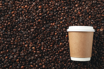 Blank coffee cup on coffee beans background, space for text