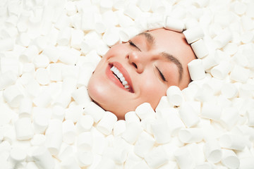 Happy woman lying amidst marshmallows