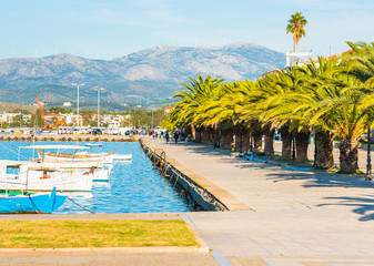 Nafplio sea promenade with palm trees and fishing boats in the water in Greece