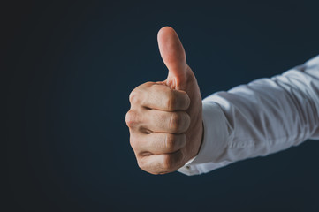 Hand of a businessman making a thumbs up gesture