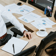 cropped view of bi-racial trader sitting at table with papers