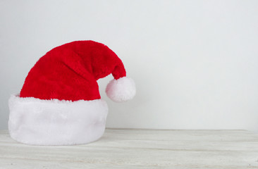 Closeup of Santa Claus hat on white wooden table isolated side over  white background. Christmas background. New Year, winter holiday, Santa cap, copy space